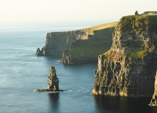 rock formation beside sea under white sky