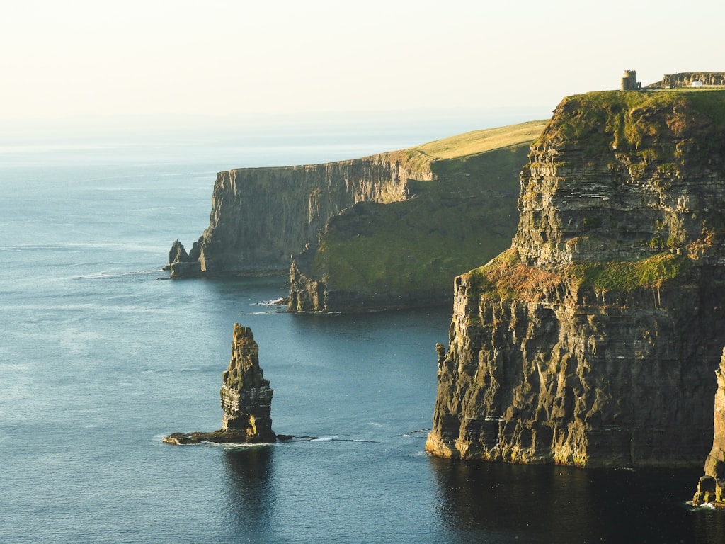 rock formation beside sea under white sky