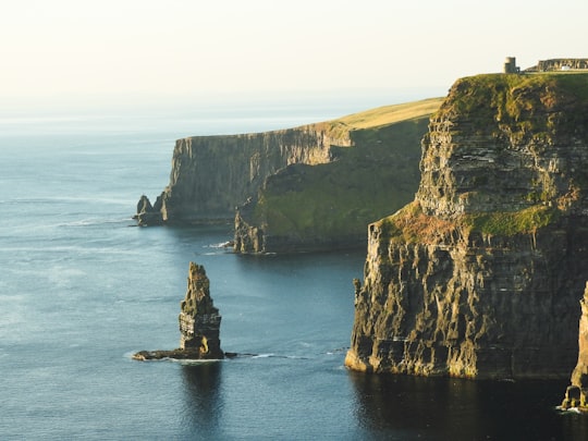 rock formation beside sea under white sky in Cliffs of Moher Ireland