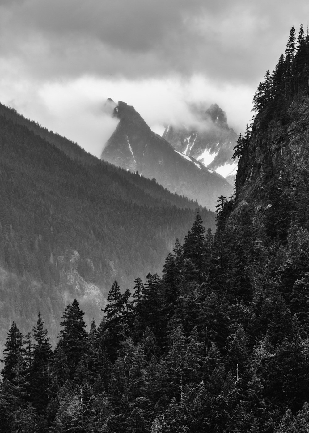 grayscale photo of mountains covered by clouds