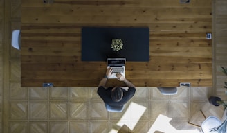 man wearing black shirt sitting on chair using laptop