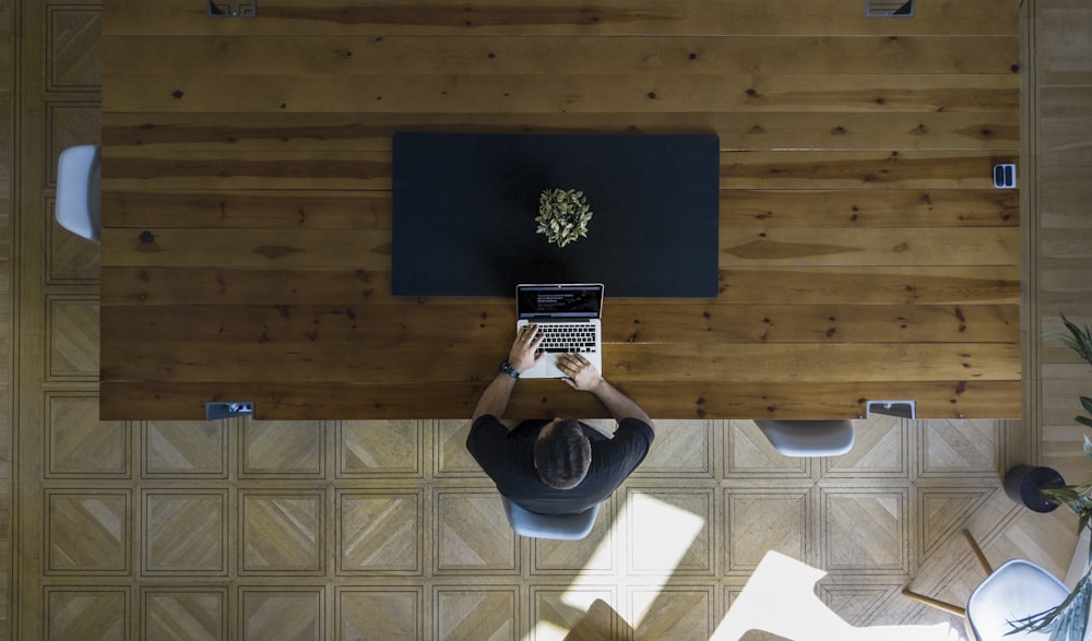 hombre con camisa negra sentado en la silla usando una computadora portátil