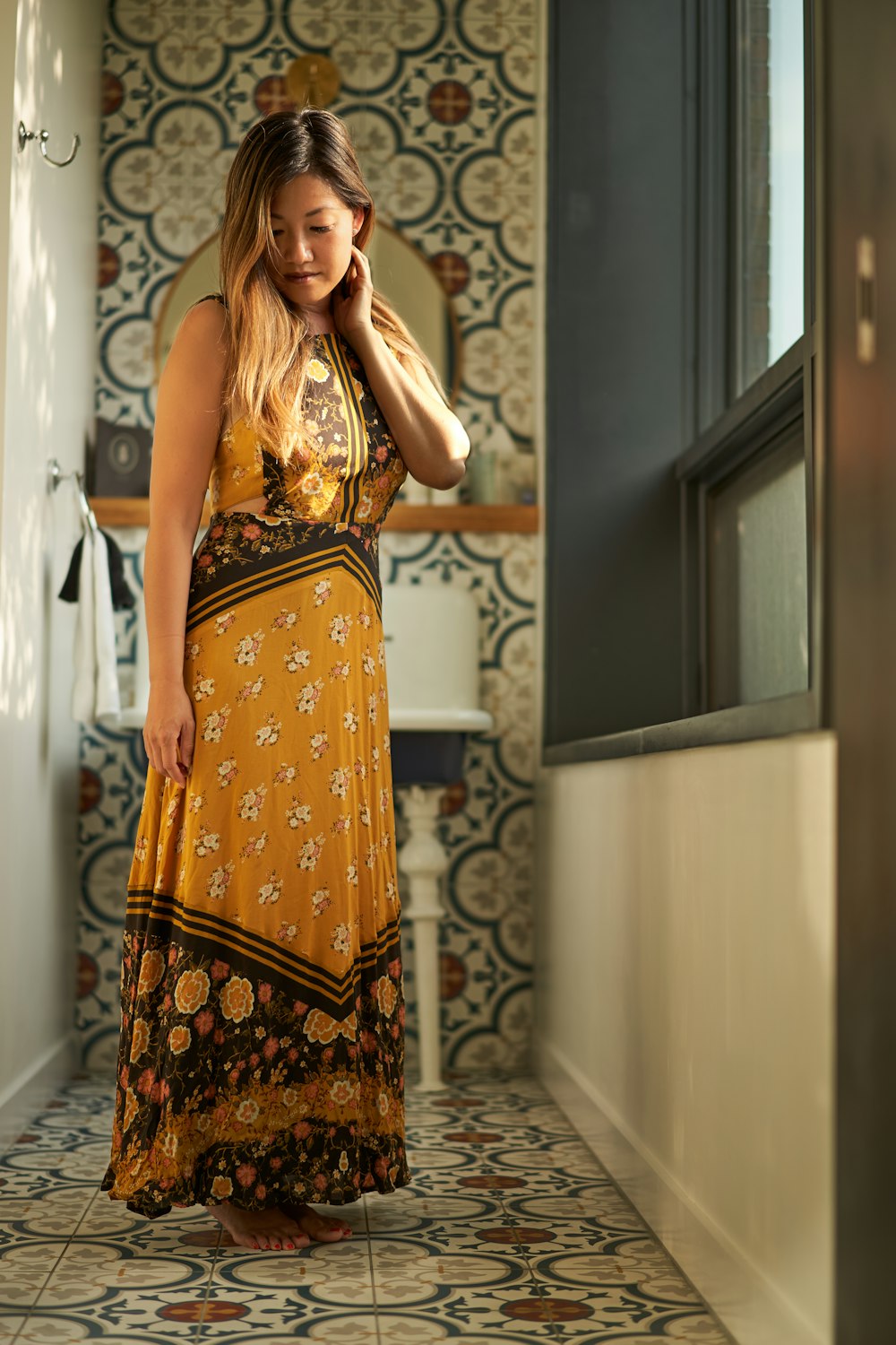 woman wearing floral dress standing near window