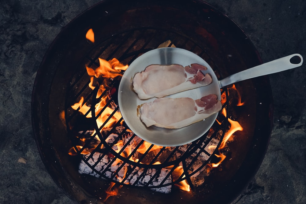 person cooking steak on charcoal gril