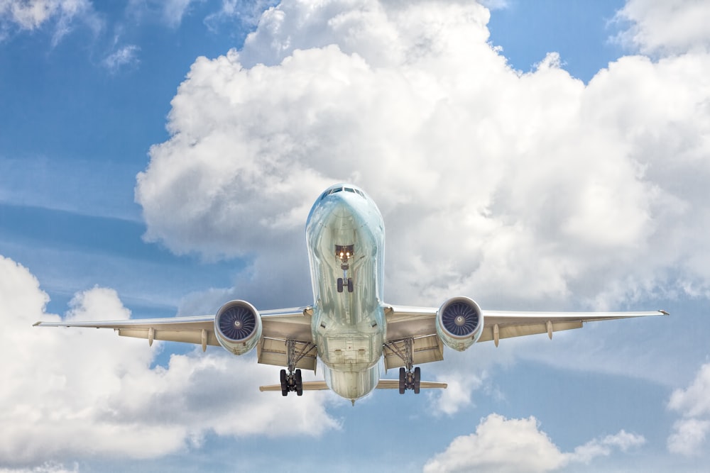 Avião cinza e branco em voo perto do céu azul claro