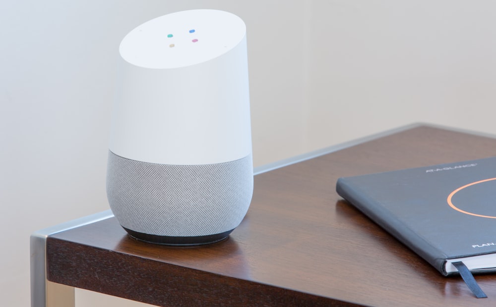 white and gray Google home on brown table