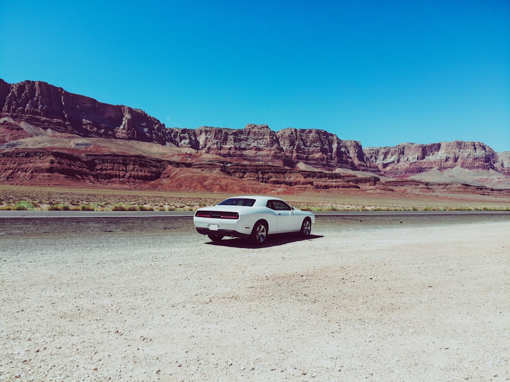 white coupe parked on desert field