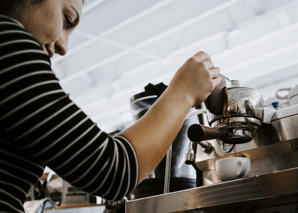 woman holding espresso machine pouring on teacup