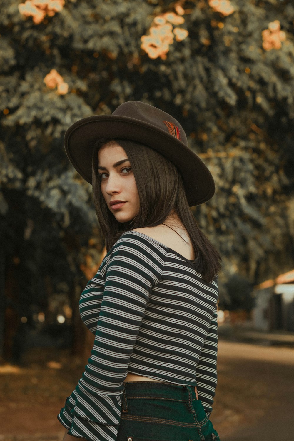 woman wearing gray and black striped shirt and black hat near green tree