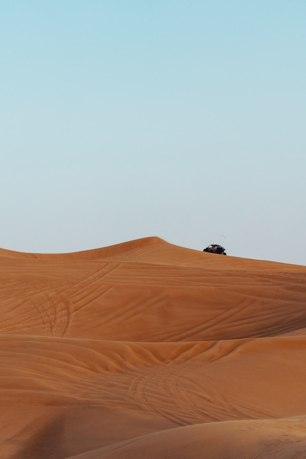 vehicle on desert under calm blue sky