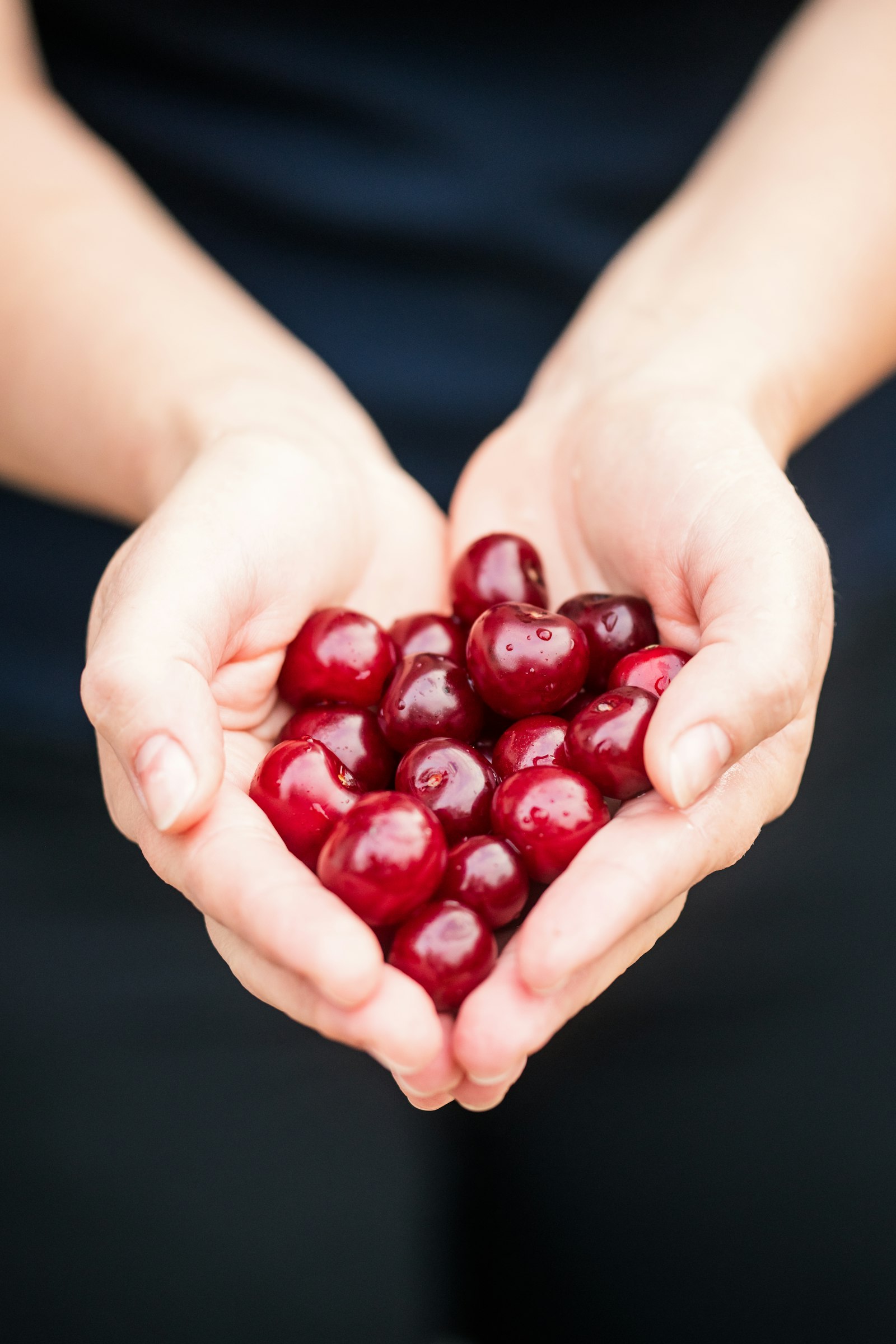 Nikon D850 + Sigma 150mm F2.8 EX DG Macro HSM sample photo. Person holding red cherries photography