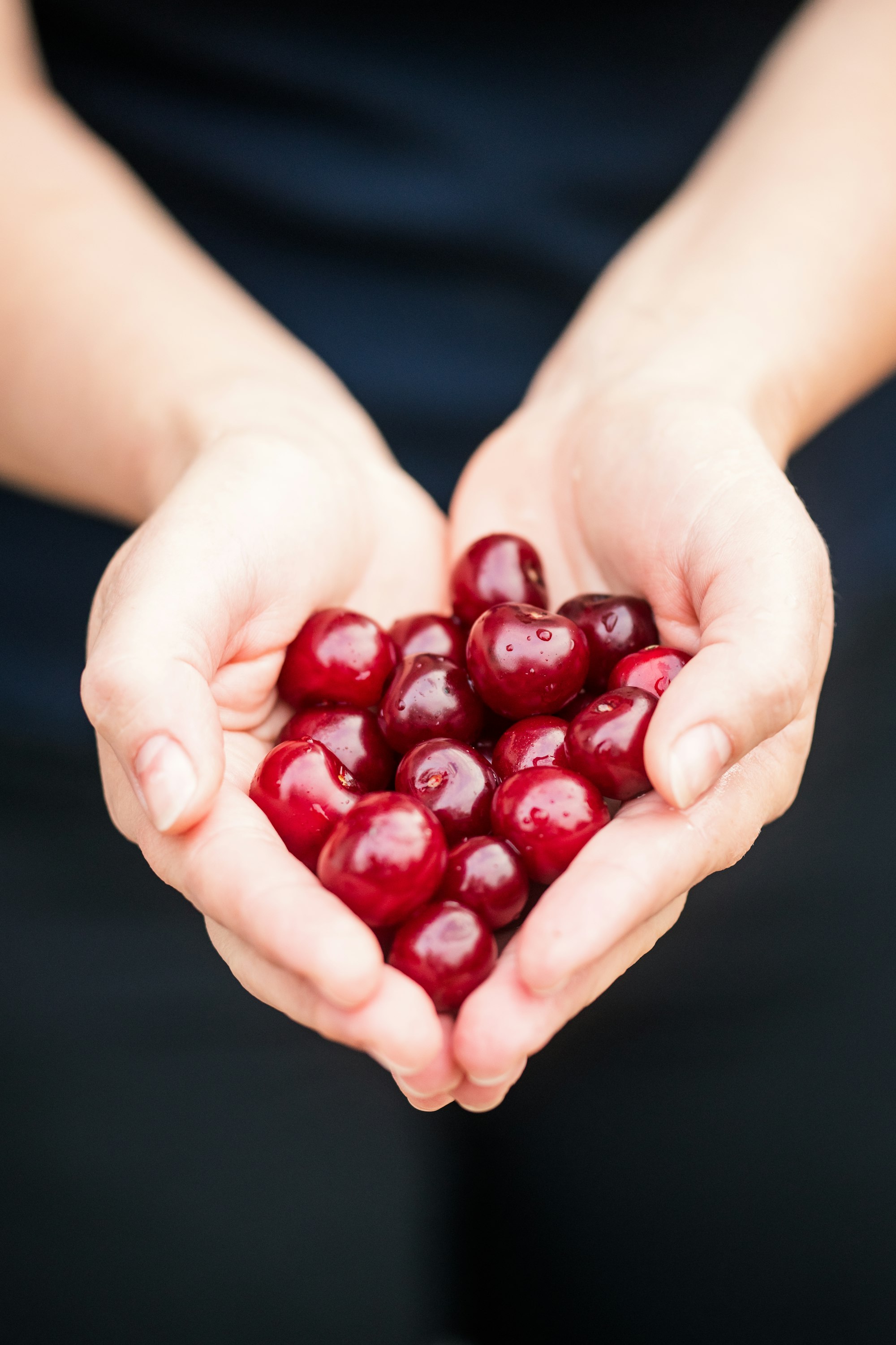 Hands full of cherries.