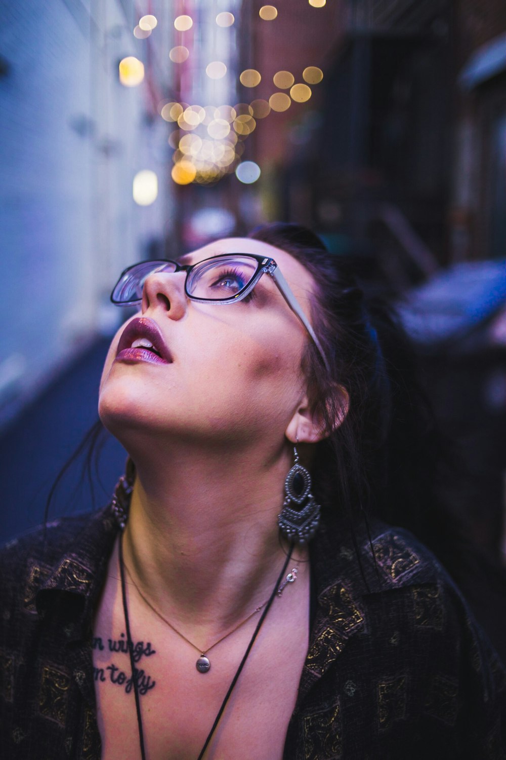 woman looking upwards wearing glasses in selective focus photography