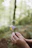 Close-up of hands gently holding a small bouquet of wildflowers against a soft beige background.