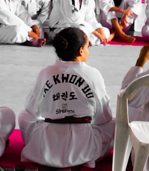 girl wearing karate gi sitting on pink puzzle mat