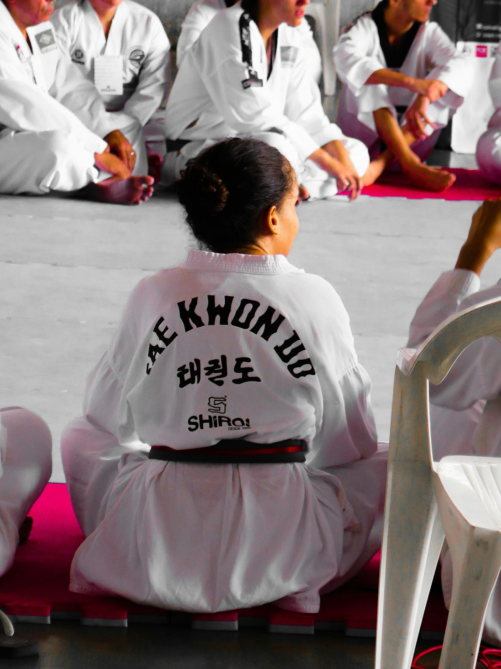 Muchacha con gi de karate sentada en estera de rompecabezas rosa