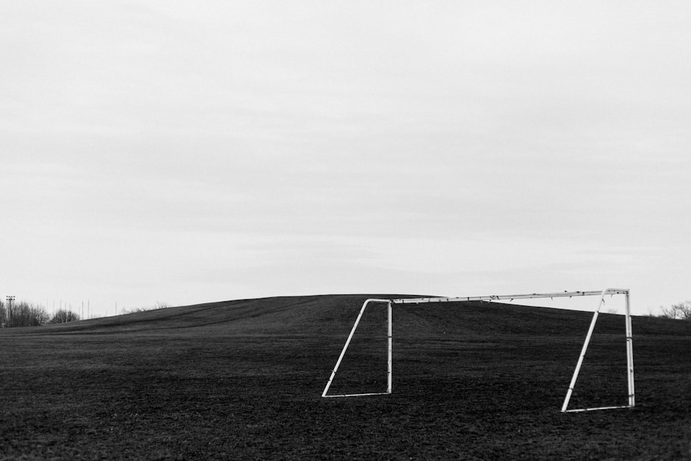 grayscale photo of white goalpost near elevated ground