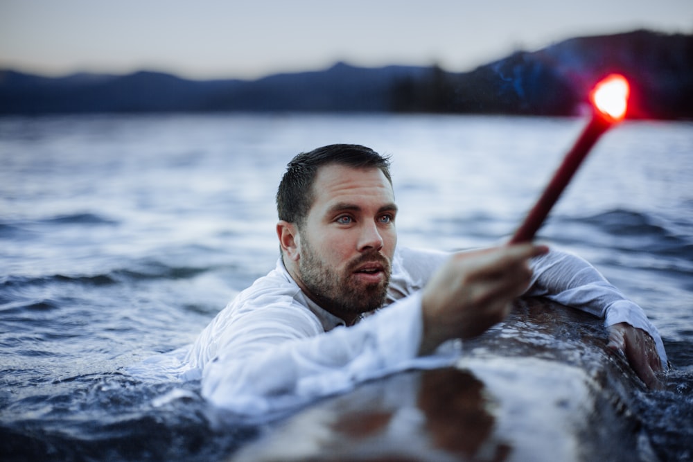 man floating on water holding wand