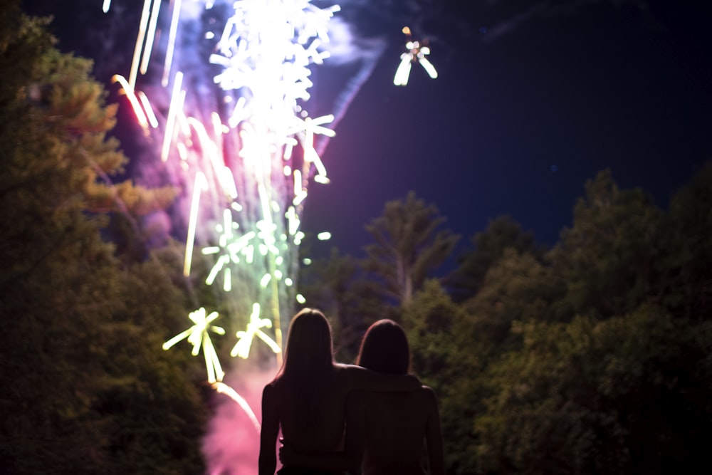 Dos personas de pie cerca del espectáculo de fuegos artificiales