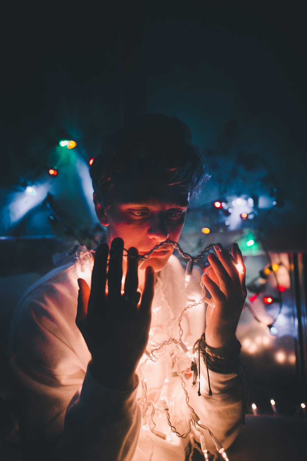 woman in white long sleeve shirt with string lights on her face