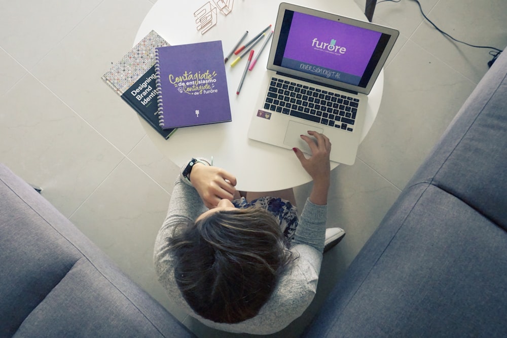 woman sitting on floor beside sectional sofa facing laptop