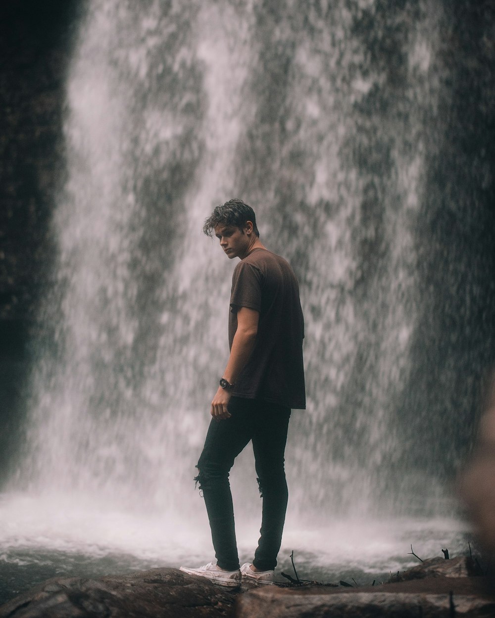 man standing near waterfall