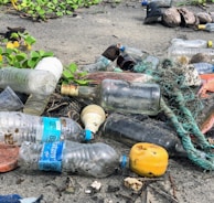 assorted garbage bottles on sandy surface