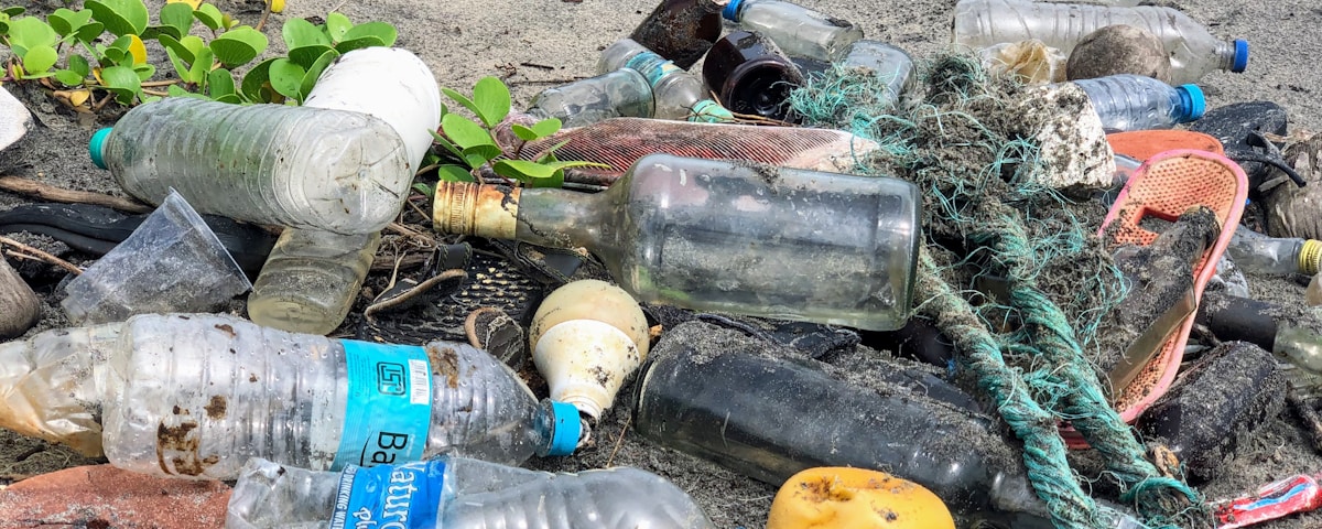 assorted garbage bottles on sandy surface