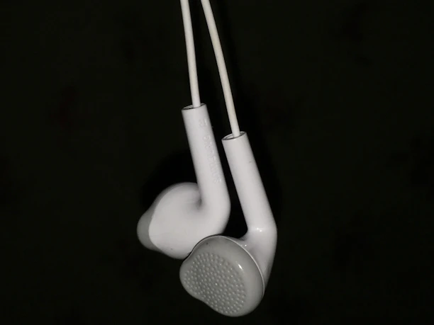 Close-up macro shot of a sleek TC4 titanium alloy in-ear monitor shell with warm gold accents against a deep black background.