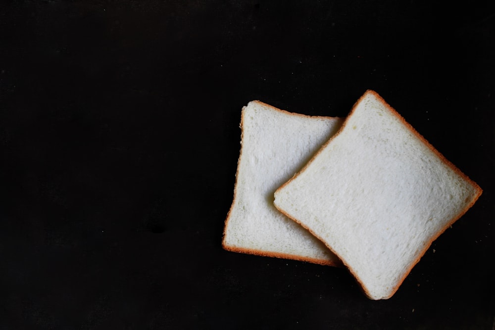 zwei Scheiben Brot auf schwarzer Oberfläche