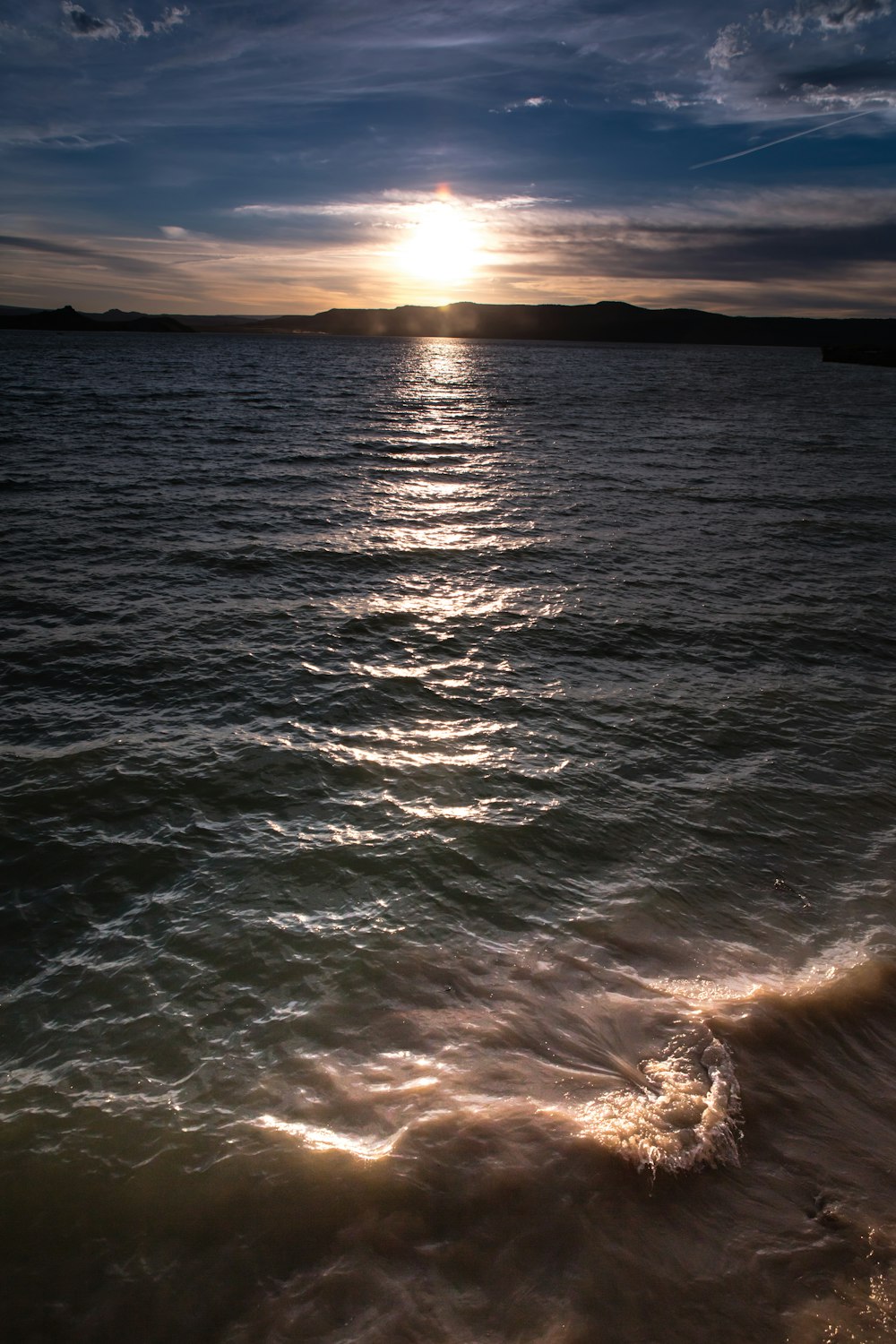 ocean waves crashing on shore during sunset