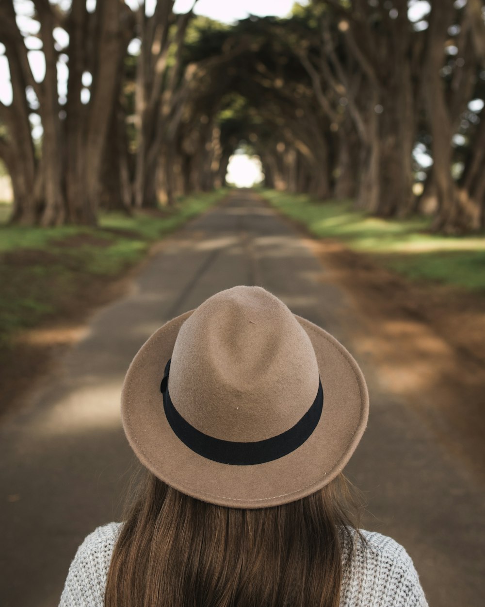 woman walking on road between trees during daytime