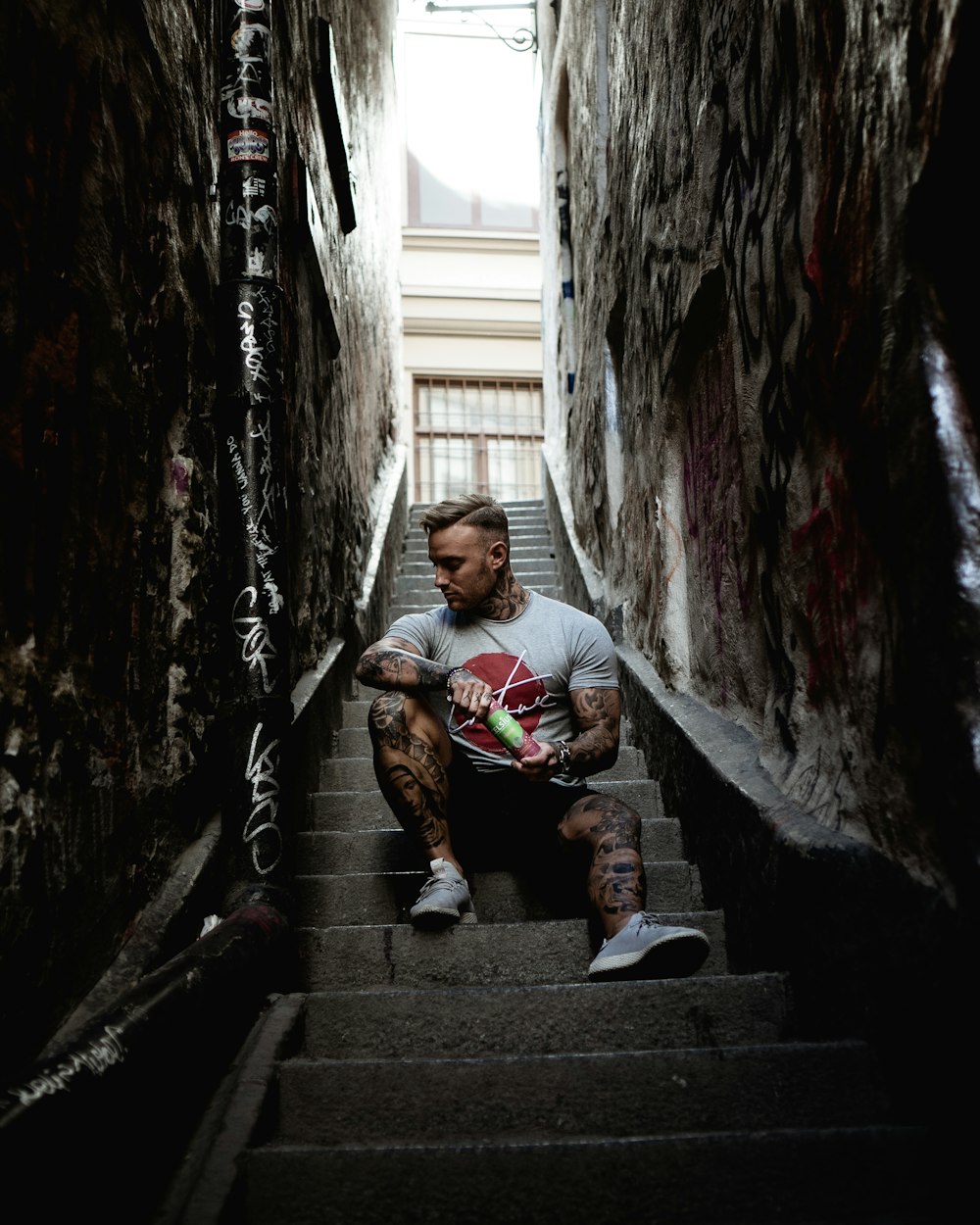 man sitting on stair in narrow pathway