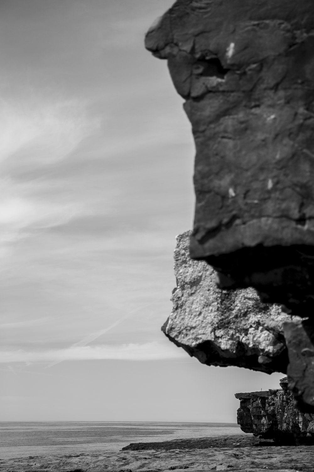 grayscale photography of cliff viewing body of water