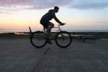 Cyclist riding an e-bike along the sandy beach path at sunset in Riviera de São Lourenço.