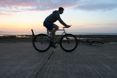 Cyclist riding an e-bike along the sandy beach path at sunset in Riviera de São Lourenço.