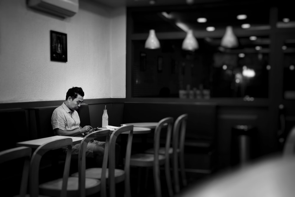 man sitting on cafe while holding smartphone