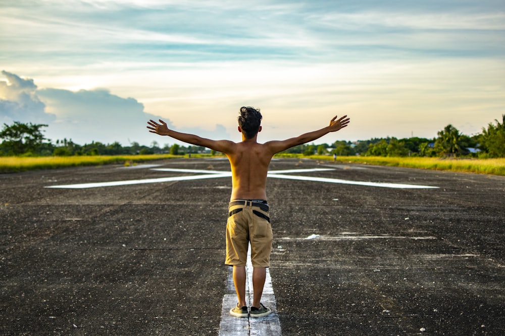 man raising hands standing on concrete road