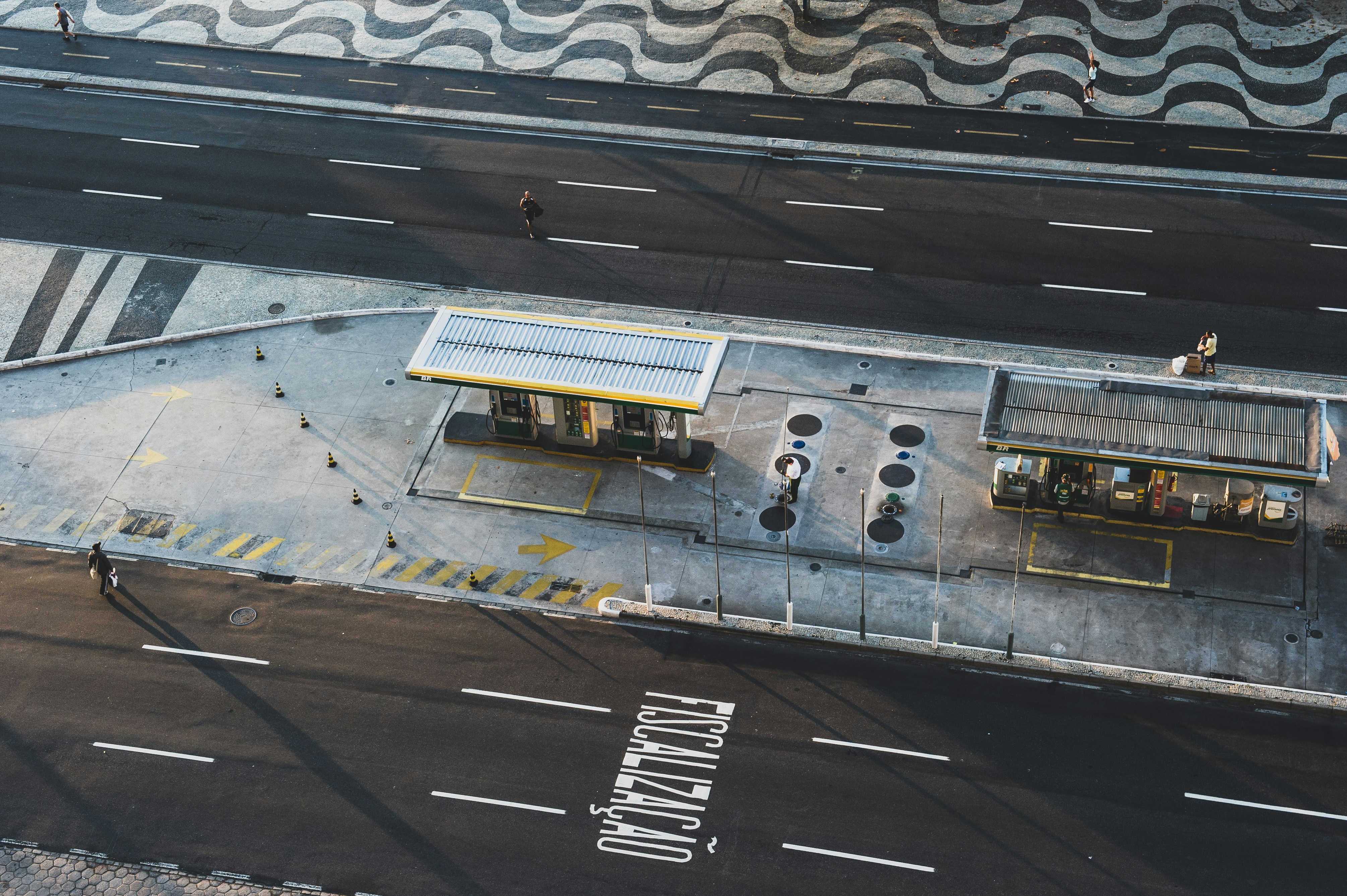 aerial photo of man walking across road approaching store