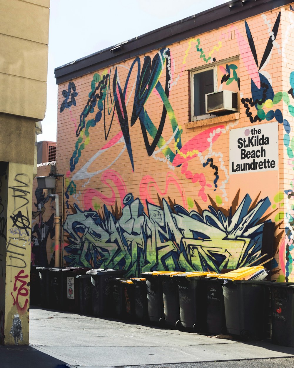 green and orange grafitti wall art beside gray alley