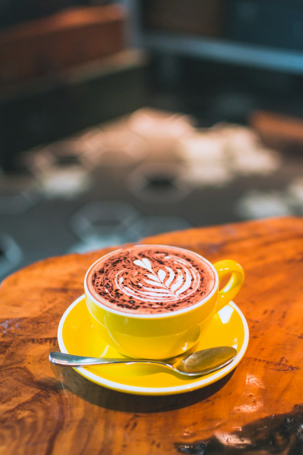 cremiges Latte-Design auf gelber Kaffeetasse mit Untertasse