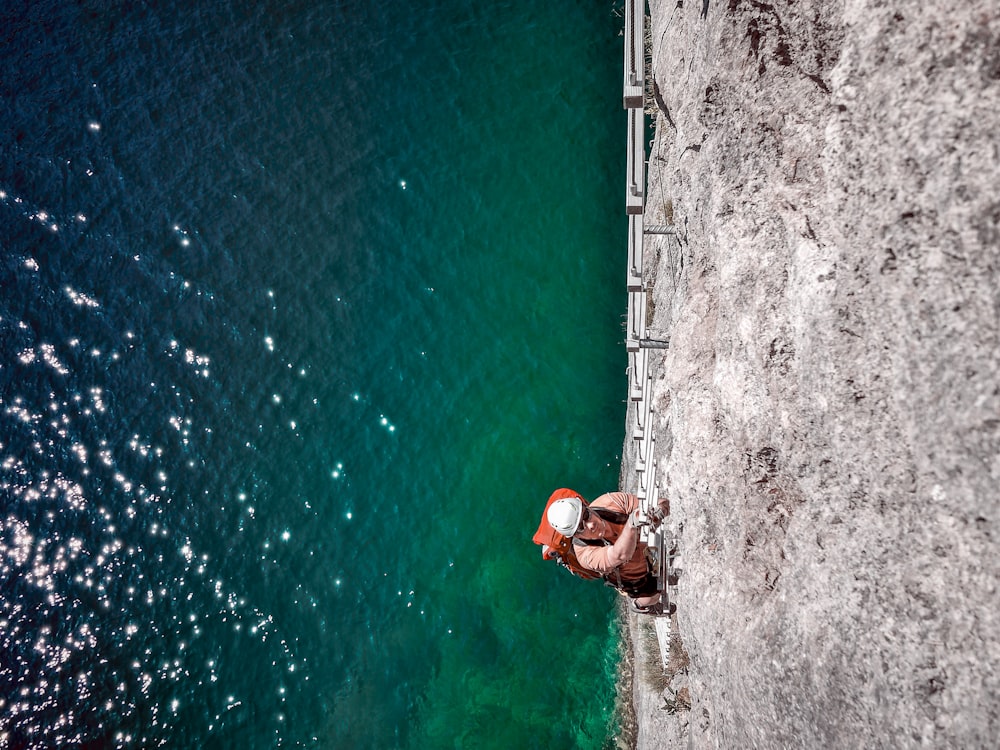 man climbing on ladder above sea level