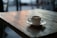 A steaming cup of coffee on a rustic wooden table with natural light.