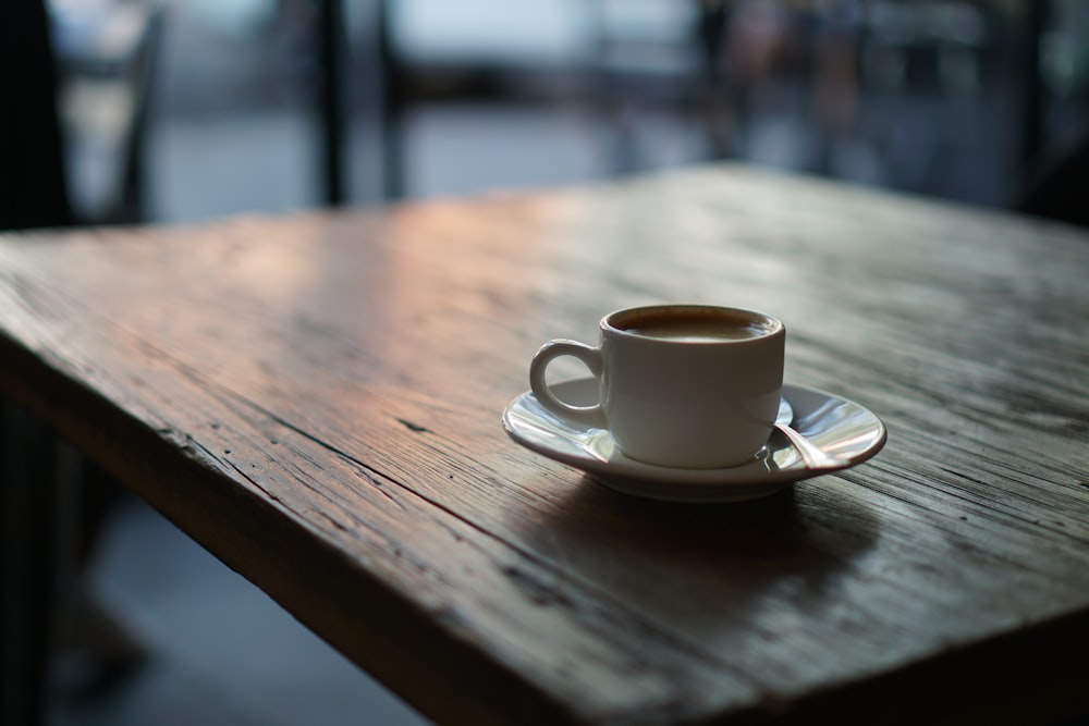 white ceramic cup on saucer on top of wooden table