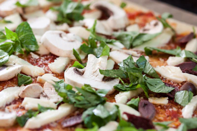 Close-up of a wood-fired pizza with fresh basil, melted mozzarella, and tomato sauce.