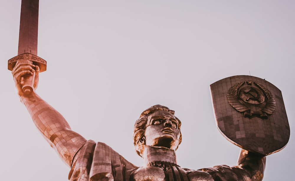 man holding shield and sword statue