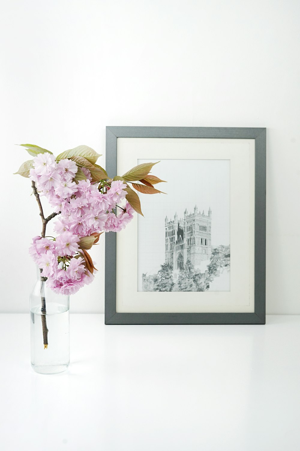Cadre photo rectangulaire en bois gris à côté de la fleur rose
