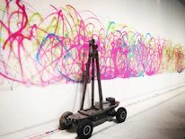 A robot painting a mural with bright, robotic hues on a city wall.
