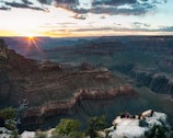 A small group of travelers admiring the vast Grand Canyon at sunset.