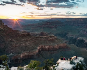 A group of happy French-speaking tourists enjoying a scenic view of the Grand Canyon at sunset.